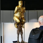 ‘The Orange Plague’: Why a golden, naked Trump is sitting on another man